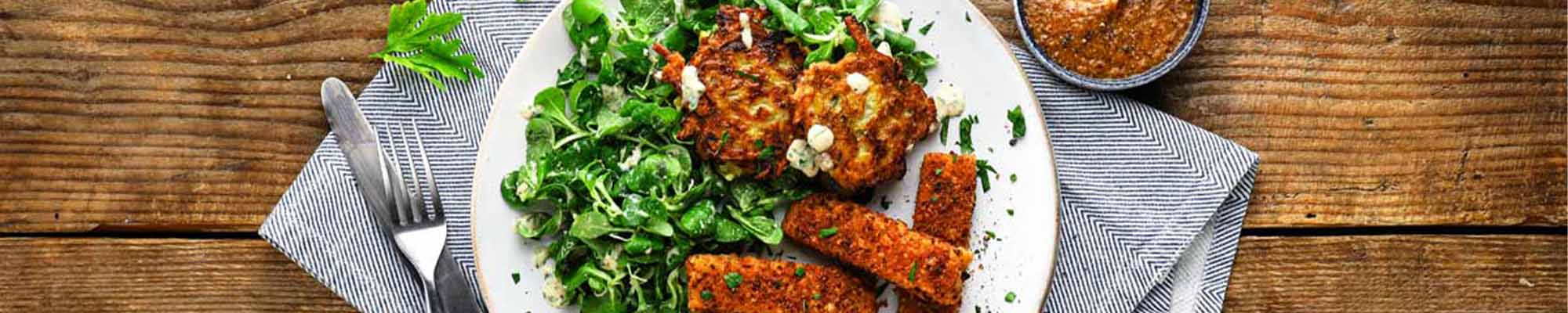 Ein Teller mit Brezel-Stäbchen mit Kartoffel-Zucchini-Puffer & Feldsalat