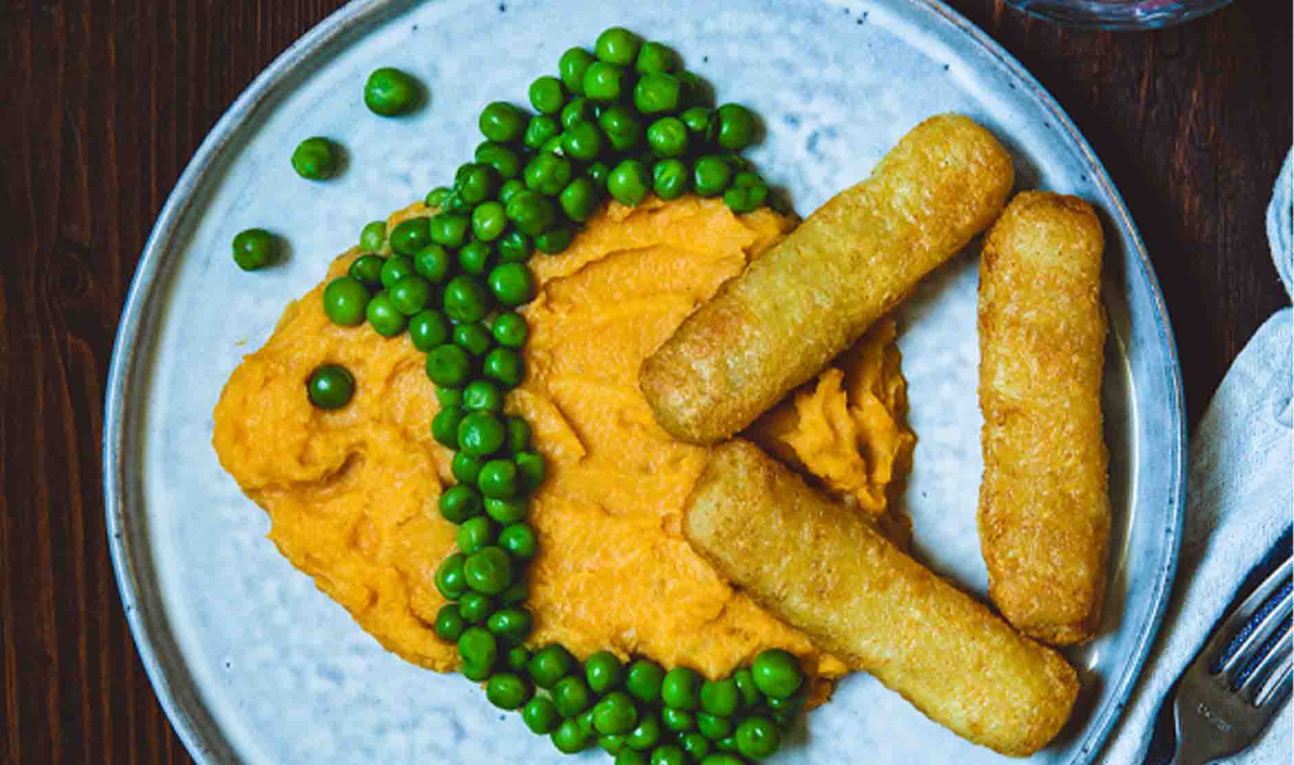 Fischstäbchen, Süßkartoffelbrei und Spinat als Fisch angerichtet auf einem Teller